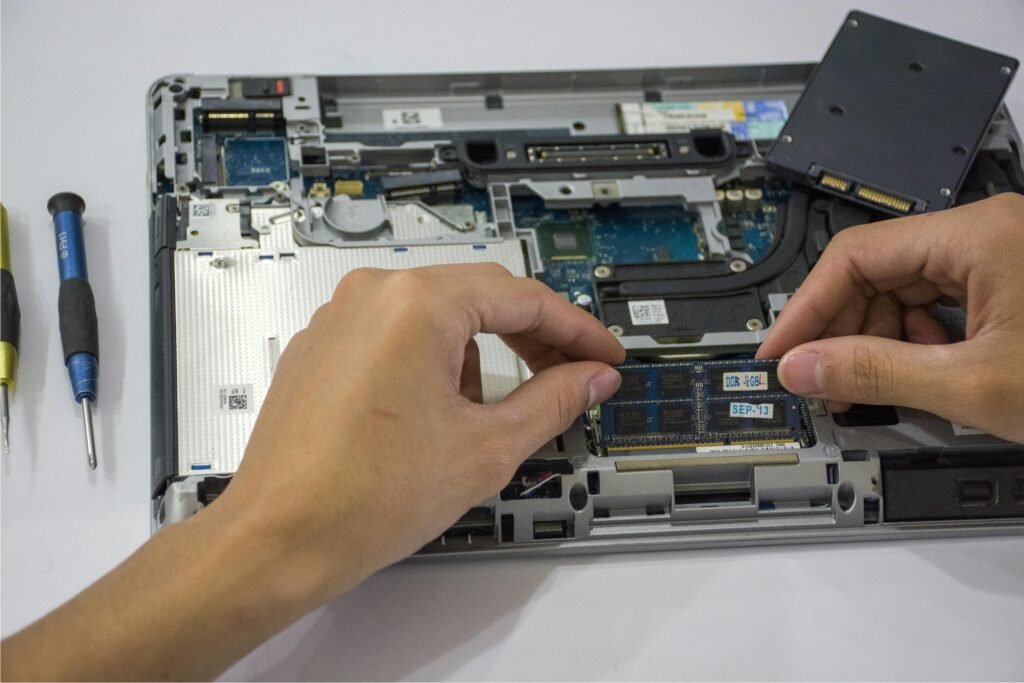 Close-up of a technician assembling a laptop's internal components using tools.