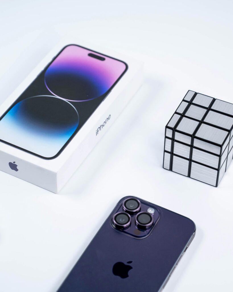 A sleek smartphone and box next to a metallic puzzle cube, emphasizing modern design.