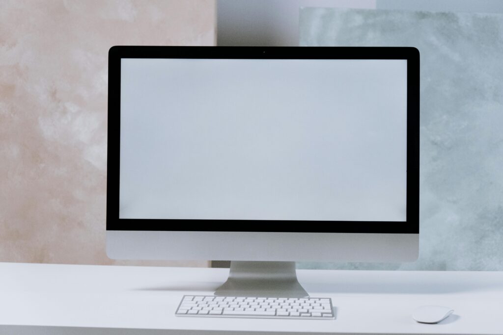 A sleek iMac desktop computer on a minimalist white desk with a keyboard and mouse.