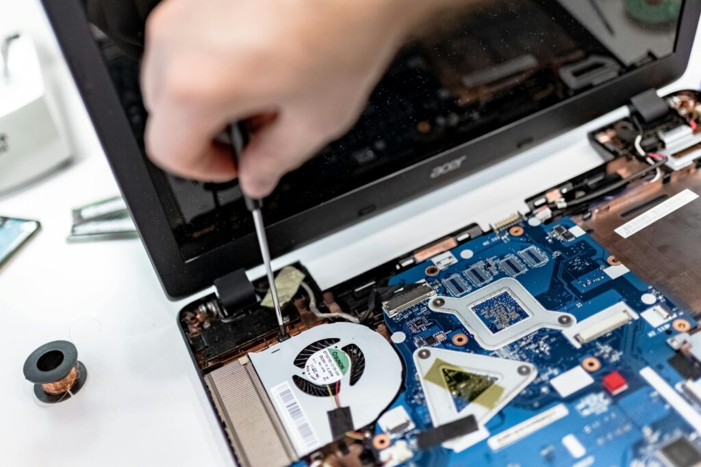 Technician repairing a laptop motherboard, focusing on electronic components.